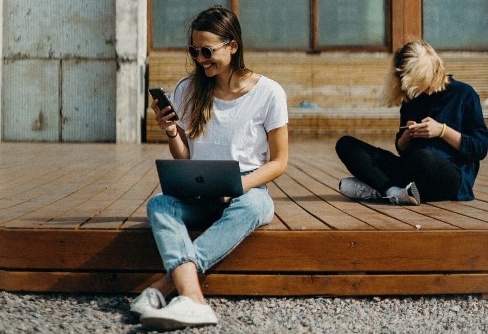 a woman working on both her laptop and phone