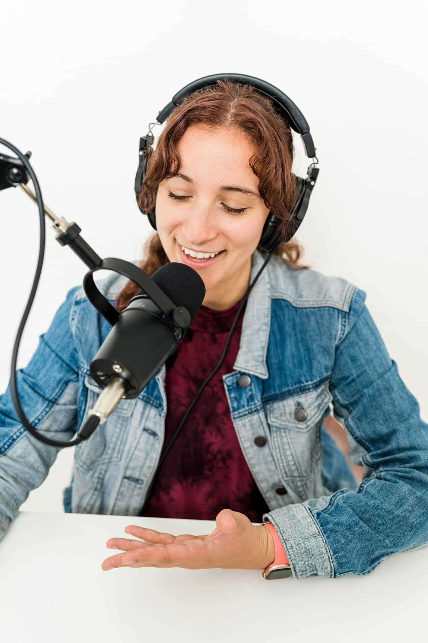 Photo of a podcaster with headphones talking into a microphone.